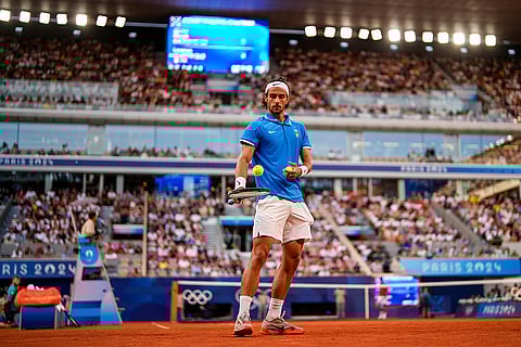 Lorenzo Musetti prepares to serve against Novak Djokovic